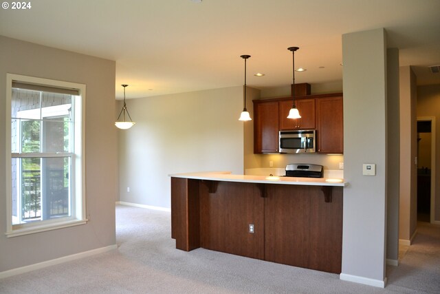 kitchen featuring kitchen peninsula, plenty of natural light, pendant lighting, and light carpet