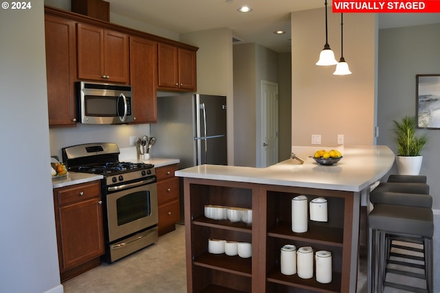 kitchen featuring a breakfast bar, decorative light fixtures, appliances with stainless steel finishes, light tile patterned floors, and kitchen peninsula