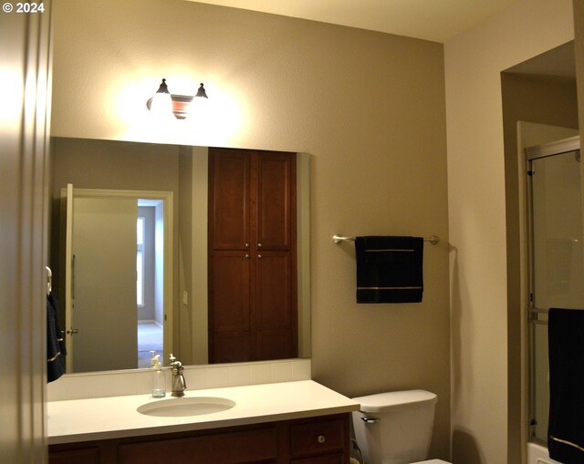 bathroom with vanity, toilet, and a shower with shower door