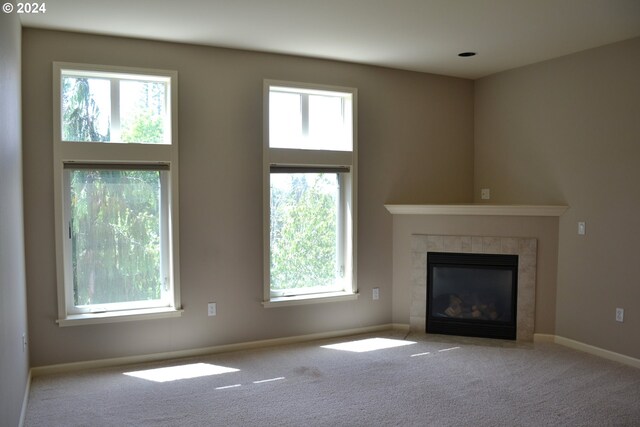 unfurnished living room featuring a towering ceiling, light colored carpet, and a fireplace