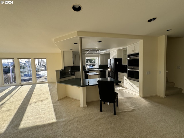 kitchen featuring plenty of natural light, kitchen peninsula, double oven, and white cabinetry