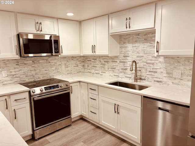 kitchen with stainless steel appliances, tasteful backsplash, light hardwood / wood-style floors, sink, and light stone counters