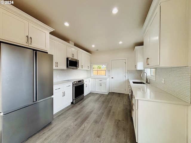 kitchen featuring light hardwood / wood-style floors, white cabinets, appliances with stainless steel finishes, and sink