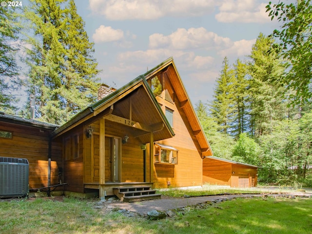 rear view of house with cooling unit, a garage, and a yard