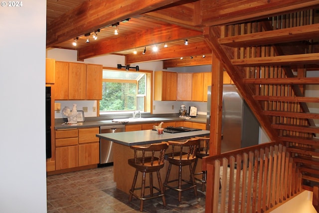 kitchen with sink, appliances with stainless steel finishes, beam ceiling, and a kitchen breakfast bar