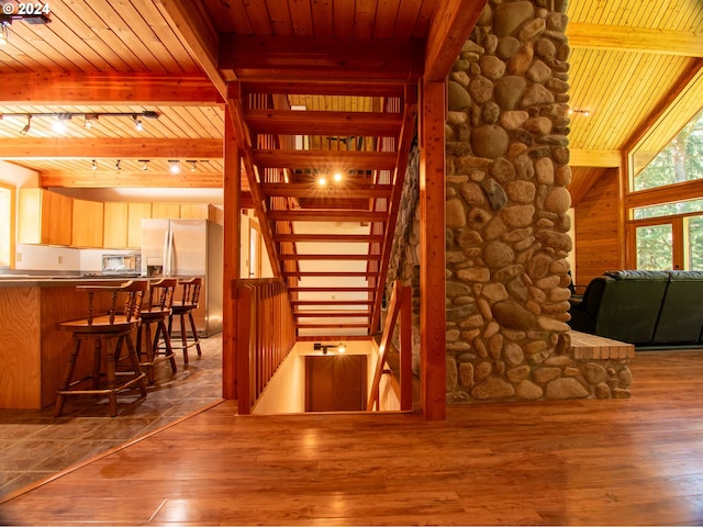 stairway with wooden ceiling, lofted ceiling with beams, and hardwood / wood-style flooring