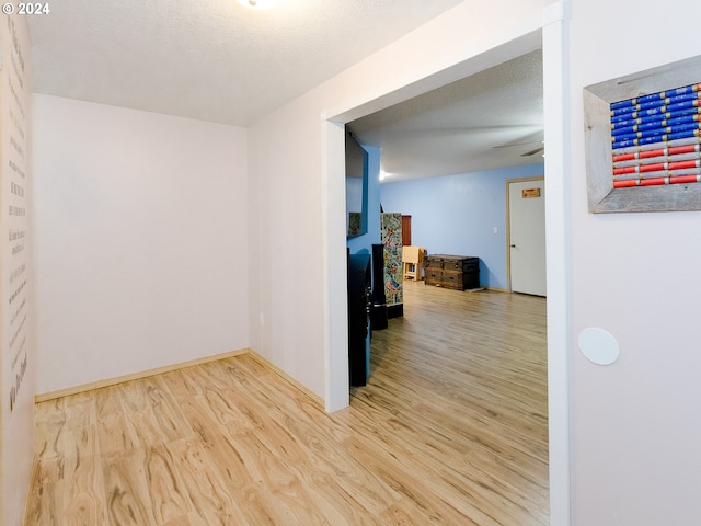 empty room with a textured ceiling, wood finished floors, and baseboards