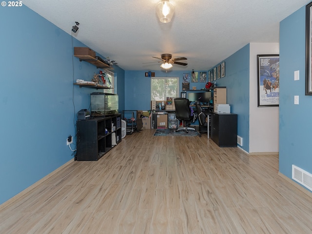 office space featuring visible vents, a ceiling fan, a textured ceiling, wood finished floors, and baseboards