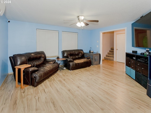 living room with light wood-type flooring, ceiling fan, stairs, and a wall mounted AC