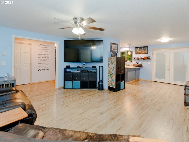 living area featuring a ceiling fan, french doors, a textured ceiling, and wood finished floors