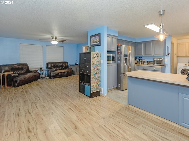 kitchen with open floor plan, appliances with stainless steel finishes, light wood-style flooring, and washer / dryer