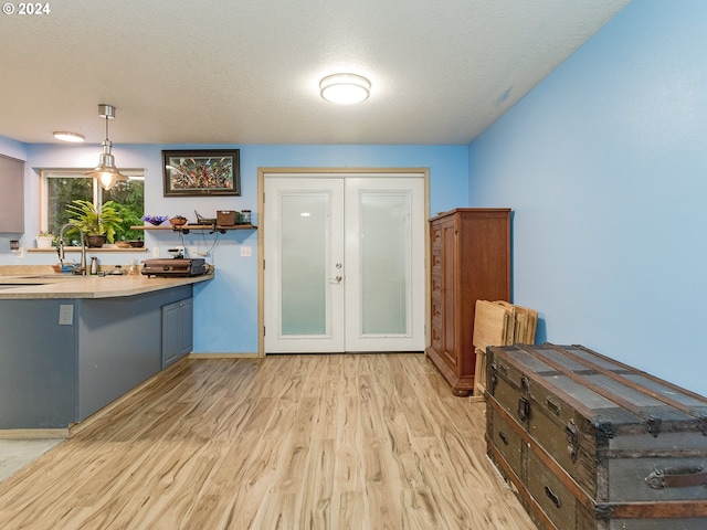 doorway to outside featuring a textured ceiling, french doors, light wood-type flooring, and a sink