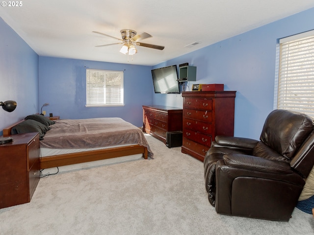 carpeted bedroom featuring ceiling fan, multiple windows, and visible vents