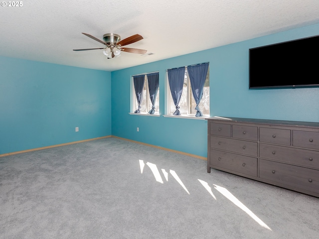 unfurnished bedroom with a textured ceiling, ceiling fan, carpet flooring, visible vents, and baseboards