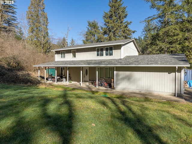 view of front of home featuring a patio, a shingled roof, and a front yard