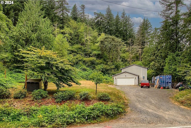 view of front facade with a garage, an outdoor structure, and a view of trees