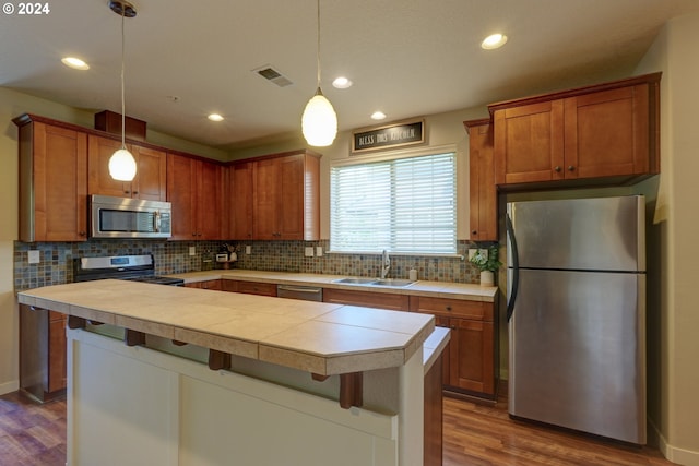 kitchen with a sink, visible vents, decorative backsplash, wood finished floors, and appliances with stainless steel finishes