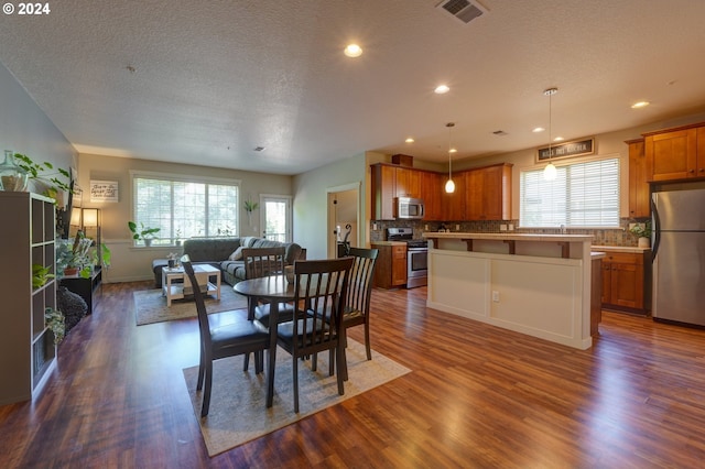 dining room featuring dark wood-type flooring, a textured ceiling, and a wealth of natural light