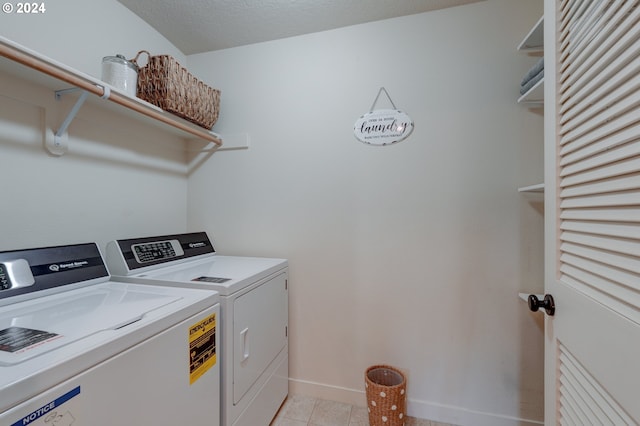 laundry area featuring baseboards, light tile patterned flooring, washer and clothes dryer, and laundry area
