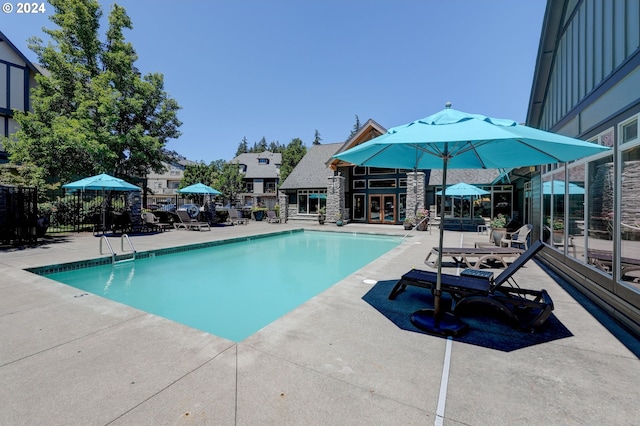 community pool with fence, a patio, and french doors