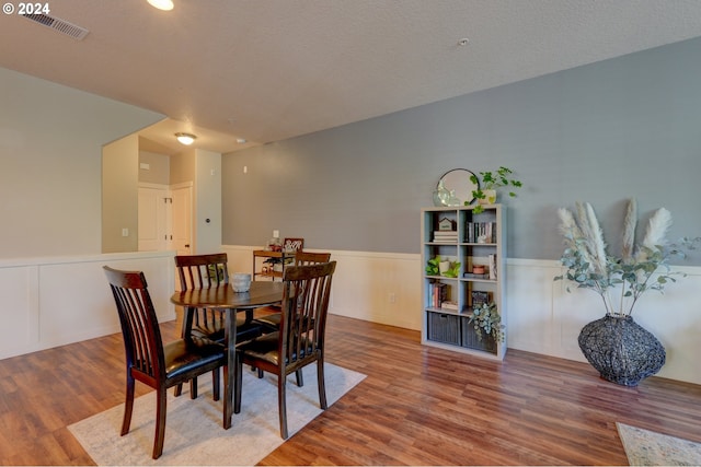 dining room featuring wood finished floors, visible vents, and a wainscoted wall