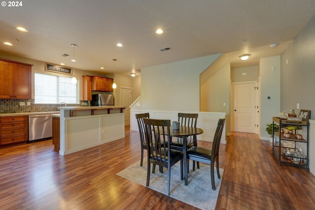 dining area with a textured ceiling and dark wood-type flooring