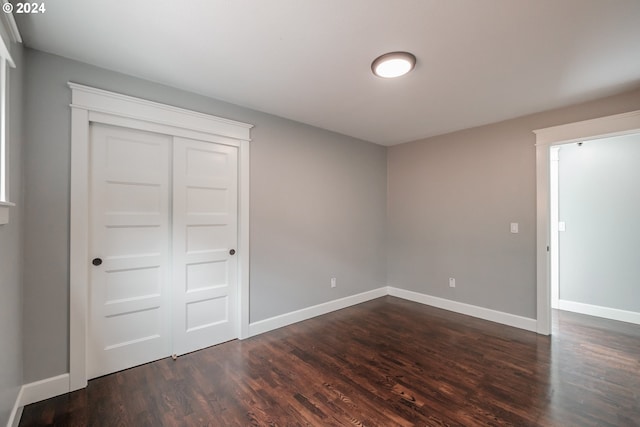 unfurnished bedroom featuring dark wood-type flooring and a closet