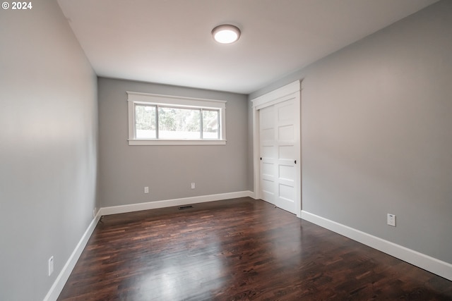 unfurnished bedroom featuring dark wood-type flooring and a closet