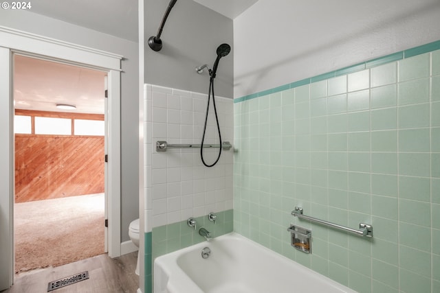 bathroom with wood-type flooring, toilet, and tiled shower / bath combo