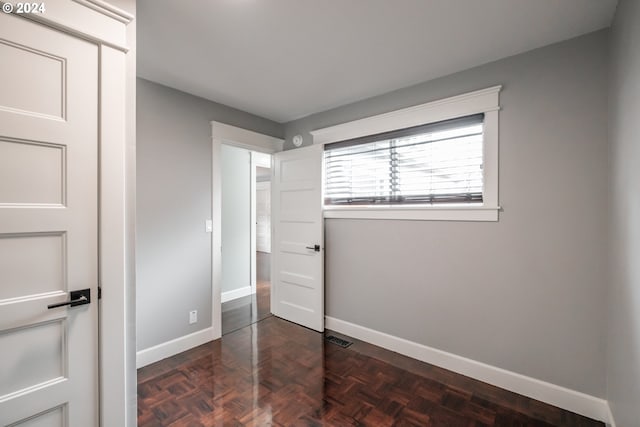 unfurnished bedroom with dark parquet flooring