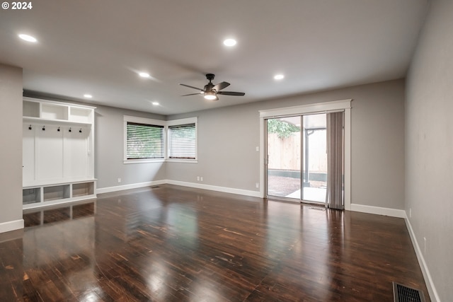 empty room with dark wood-type flooring, ceiling fan, and a healthy amount of sunlight