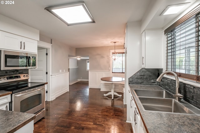 kitchen featuring sink, white cabinetry, hanging light fixtures, dark hardwood / wood-style floors, and stainless steel appliances