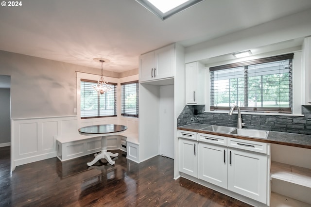 kitchen featuring decorative light fixtures, tasteful backsplash, white cabinetry, sink, and dark hardwood / wood-style flooring