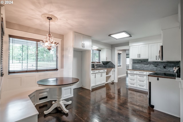 kitchen with a wealth of natural light, dark hardwood / wood-style flooring, hanging light fixtures, and white cabinets