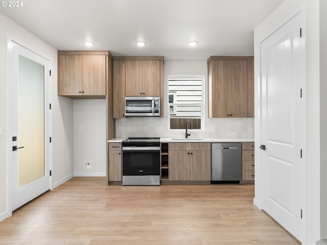 kitchen featuring decorative backsplash, sink, stainless steel appliances, and light hardwood / wood-style floors