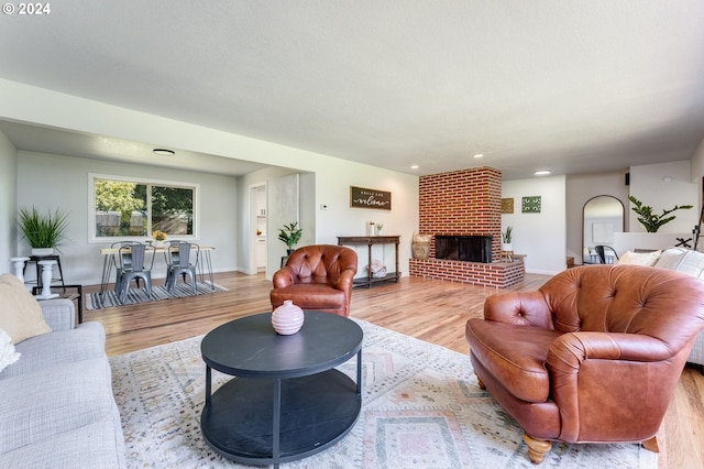 living room with a brick fireplace and light hardwood / wood-style flooring