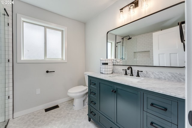 bathroom with tiled shower, vanity, and toilet