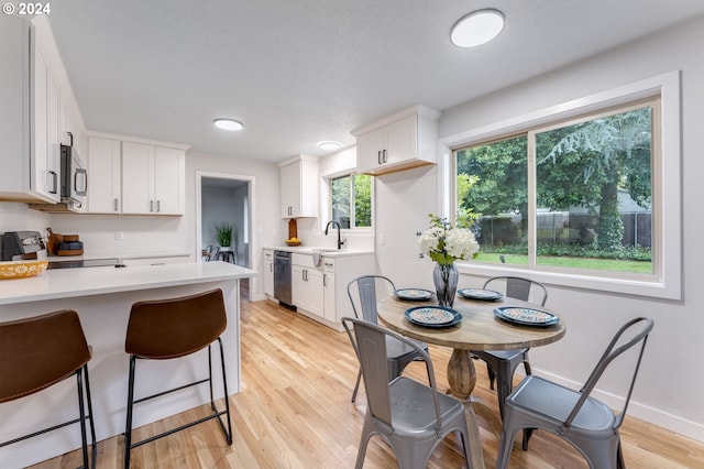 kitchen featuring appliances with stainless steel finishes, light hardwood / wood-style floors, white cabinets, and sink