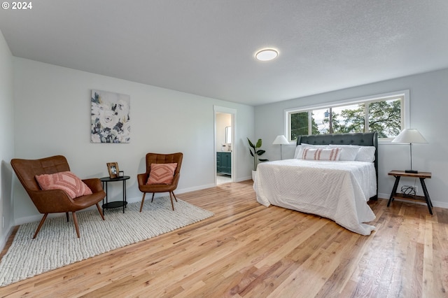 bedroom with ensuite bath and light hardwood / wood-style floors