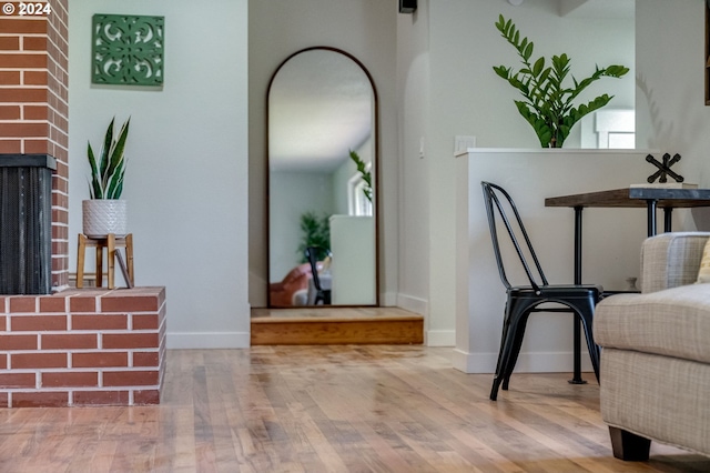 living area with a brick fireplace and wood-type flooring