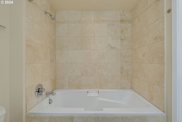 bathroom featuring toilet and tiled shower / bath