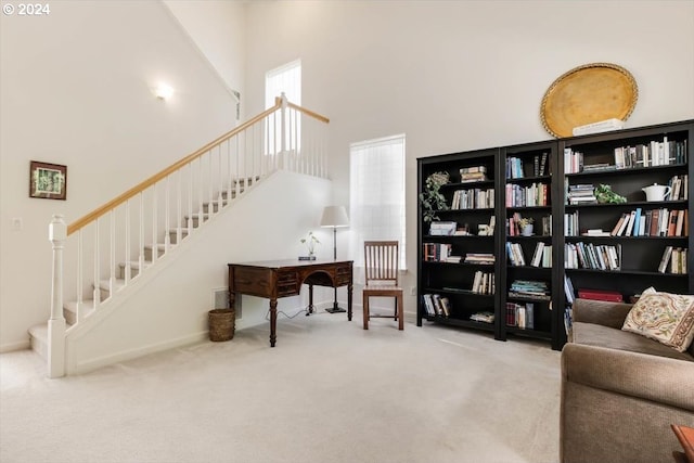 sitting room featuring carpet floors and a towering ceiling