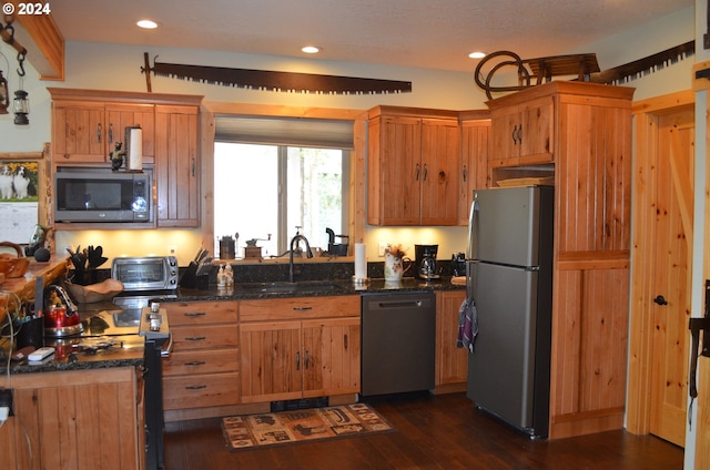 kitchen featuring appliances with stainless steel finishes, dark hardwood / wood-style floors, sink, and dark stone counters