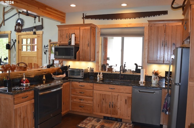 kitchen featuring dark stone countertops, sink, beamed ceiling, and stainless steel appliances