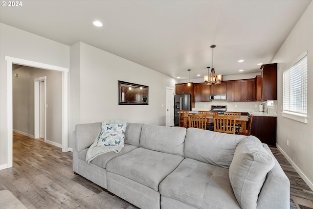 living room with light hardwood / wood-style flooring, a notable chandelier, and sink