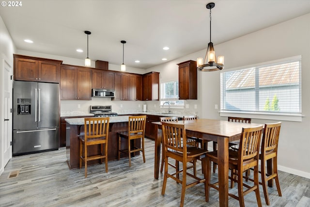 dining space featuring sink, a notable chandelier, and light wood-type flooring