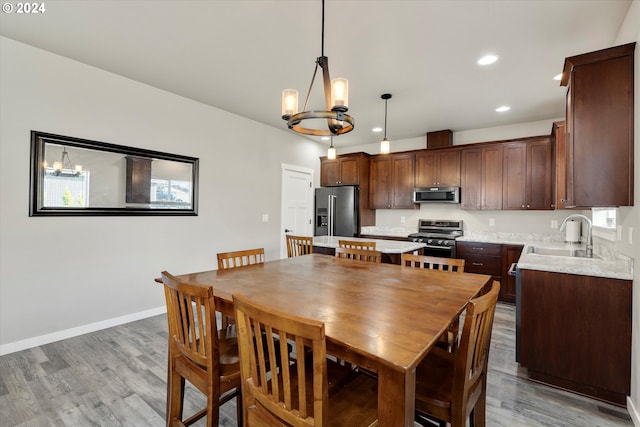 dining area featuring light hardwood / wood-style flooring, sink, and an inviting chandelier