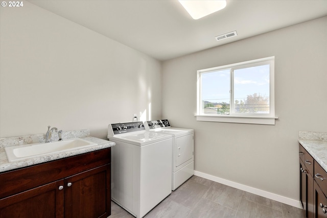 laundry room with washing machine and clothes dryer, cabinets, and sink