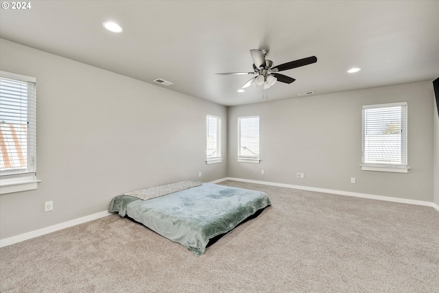 carpeted bedroom with multiple windows and ceiling fan