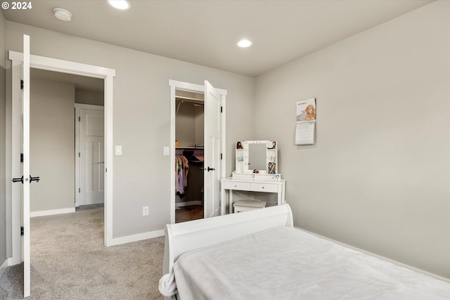 bedroom featuring light carpet, a walk in closet, and a closet